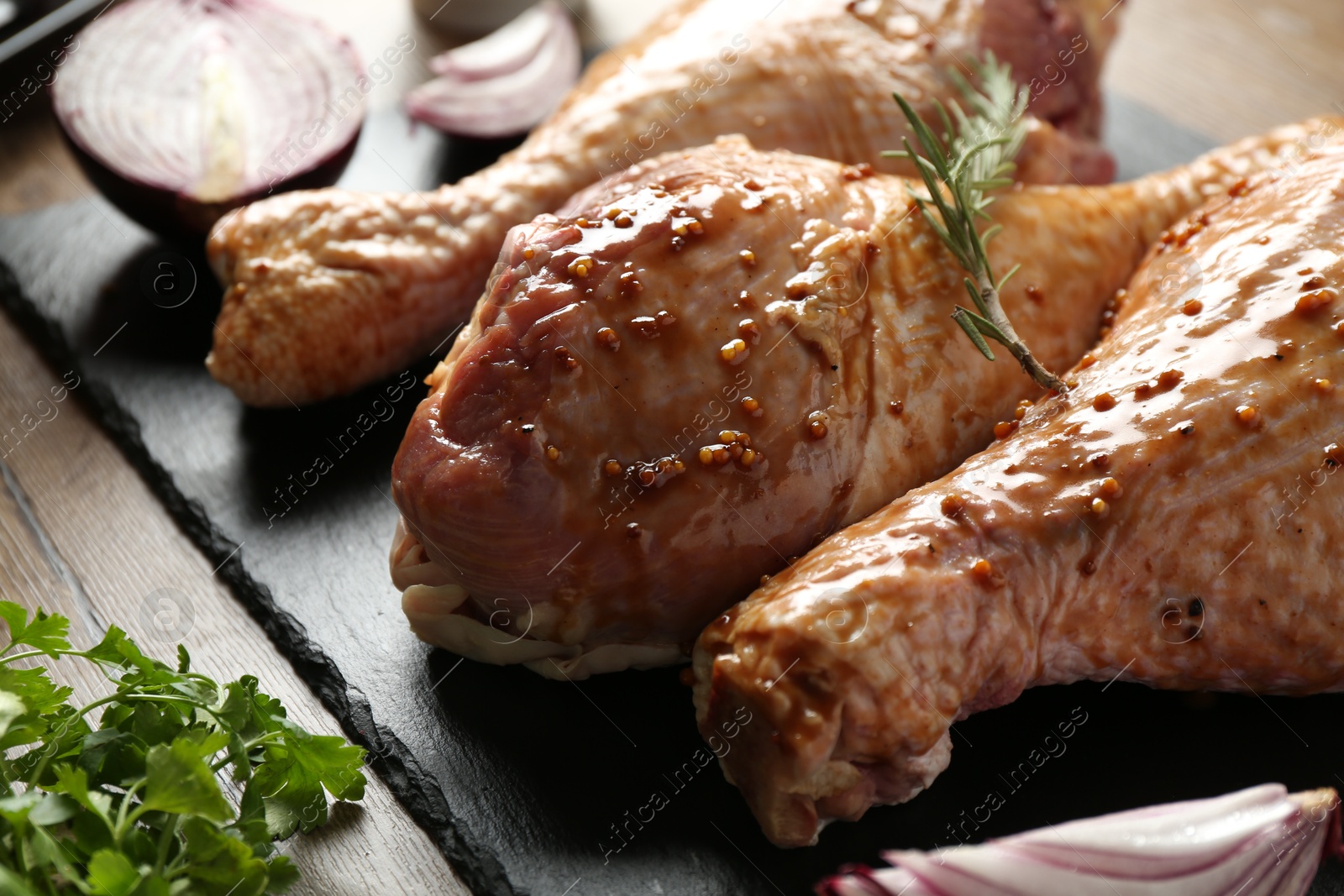 Photo of Raw marinated turkey drumsticks on wooden table, closeup