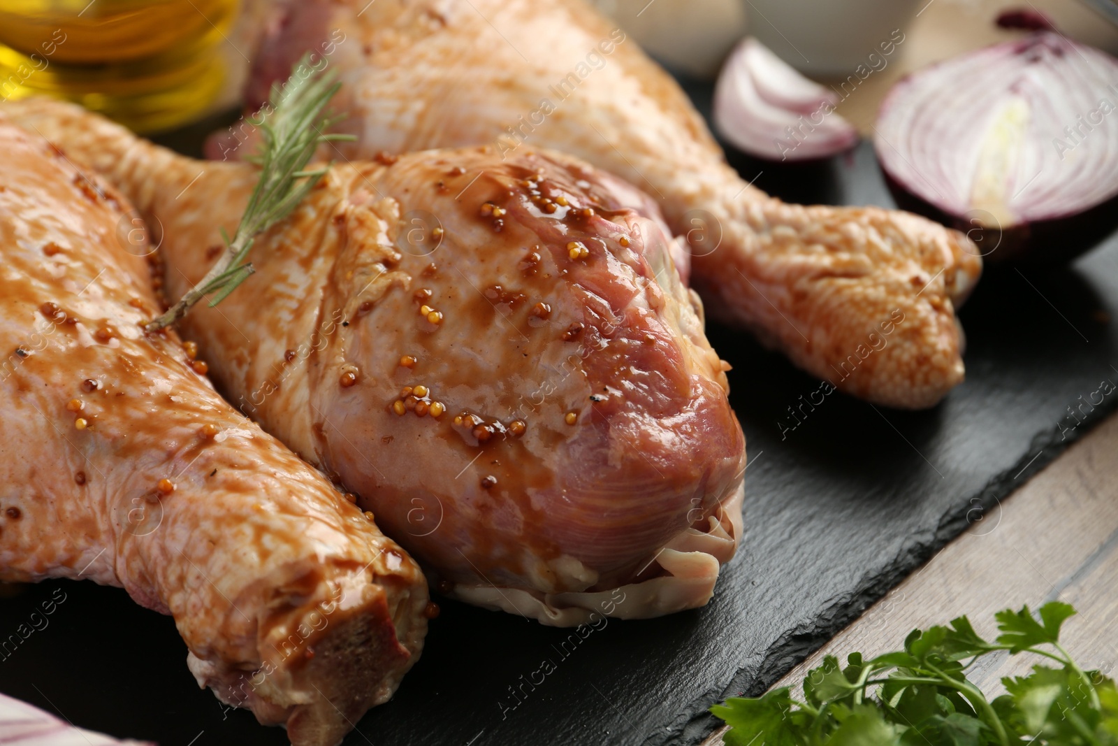 Photo of Raw marinated turkey drumsticks on wooden table, closeup