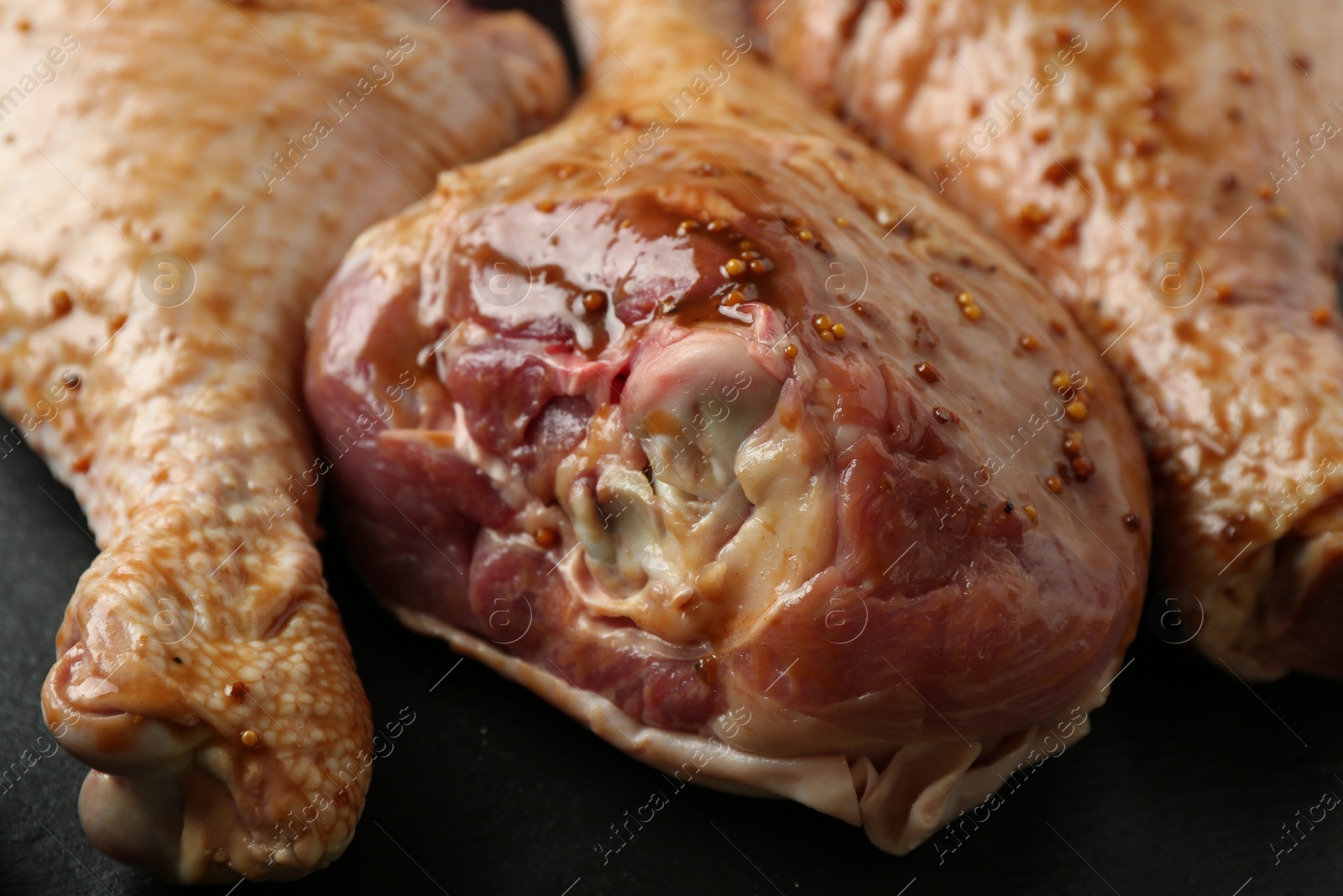 Photo of Raw marinated turkey drumsticks on table, closeup