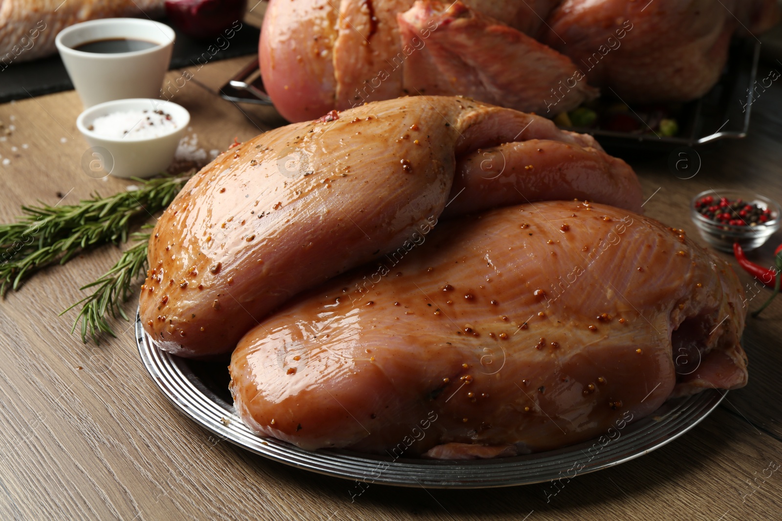 Photo of Raw marinated turkey breasts on wooden table, closeup