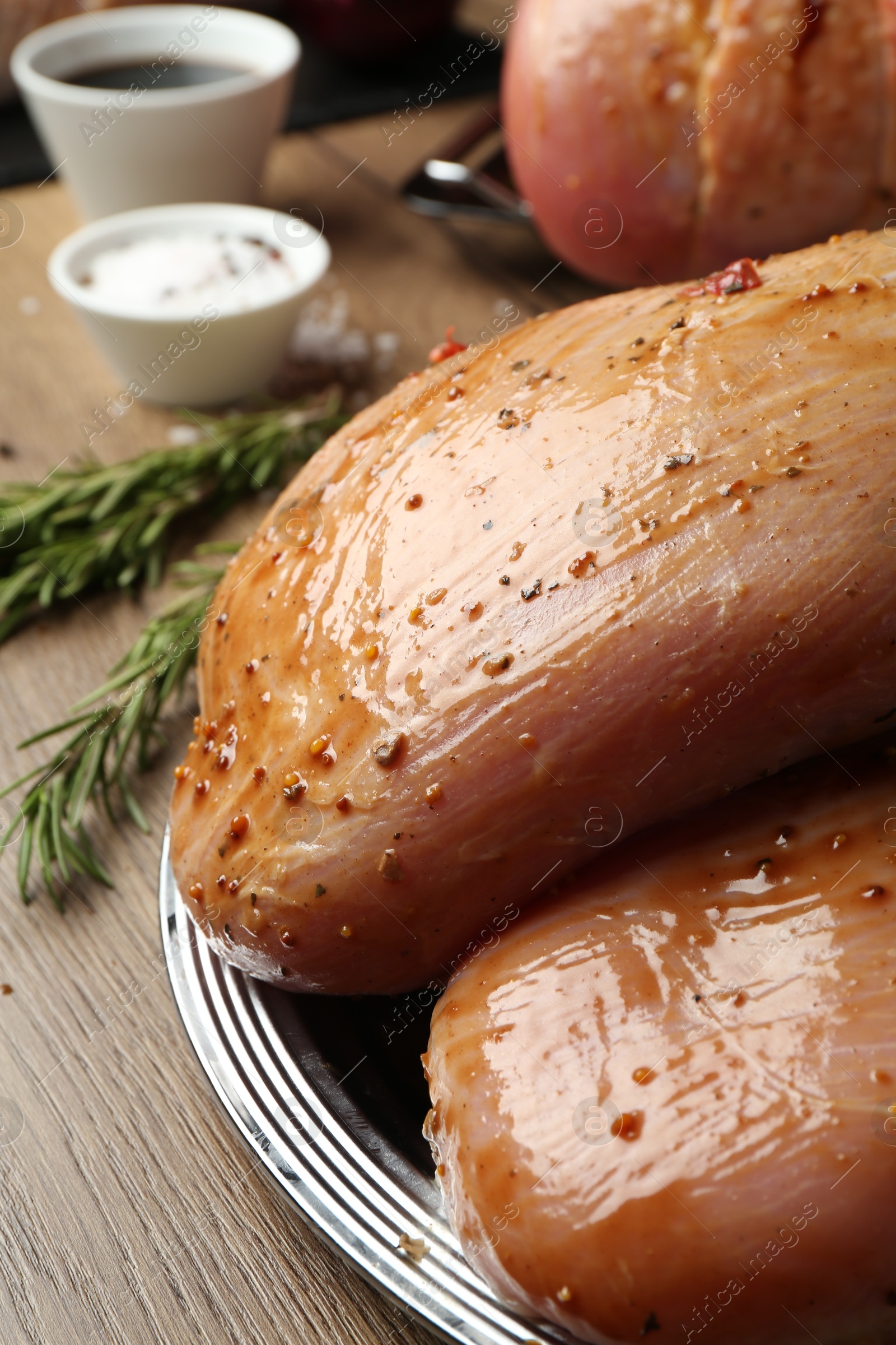 Photo of Raw marinated turkey breasts on wooden table, closeup