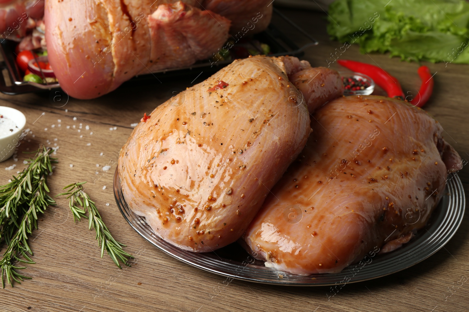 Photo of Raw marinated turkey breasts on wooden table, closeup