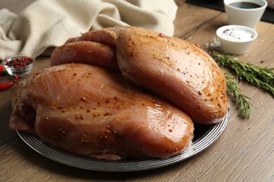 Photo of Raw marinated turkey breasts on wooden table, closeup