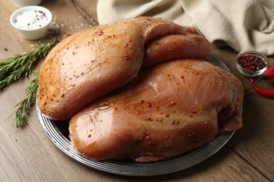 Photo of Raw marinated turkey breasts on wooden table, closeup