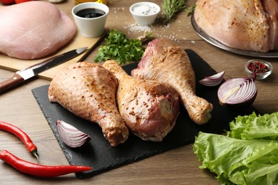 Photo of Raw marinated turkey drumsticks on wooden table