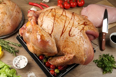 Photo of Whole raw marinated turkey and products on wooden table