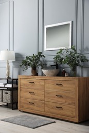 Photo of Modern bathroom interior with stylish mirror, eucalyptus branches, vessel sink and wooden vanity