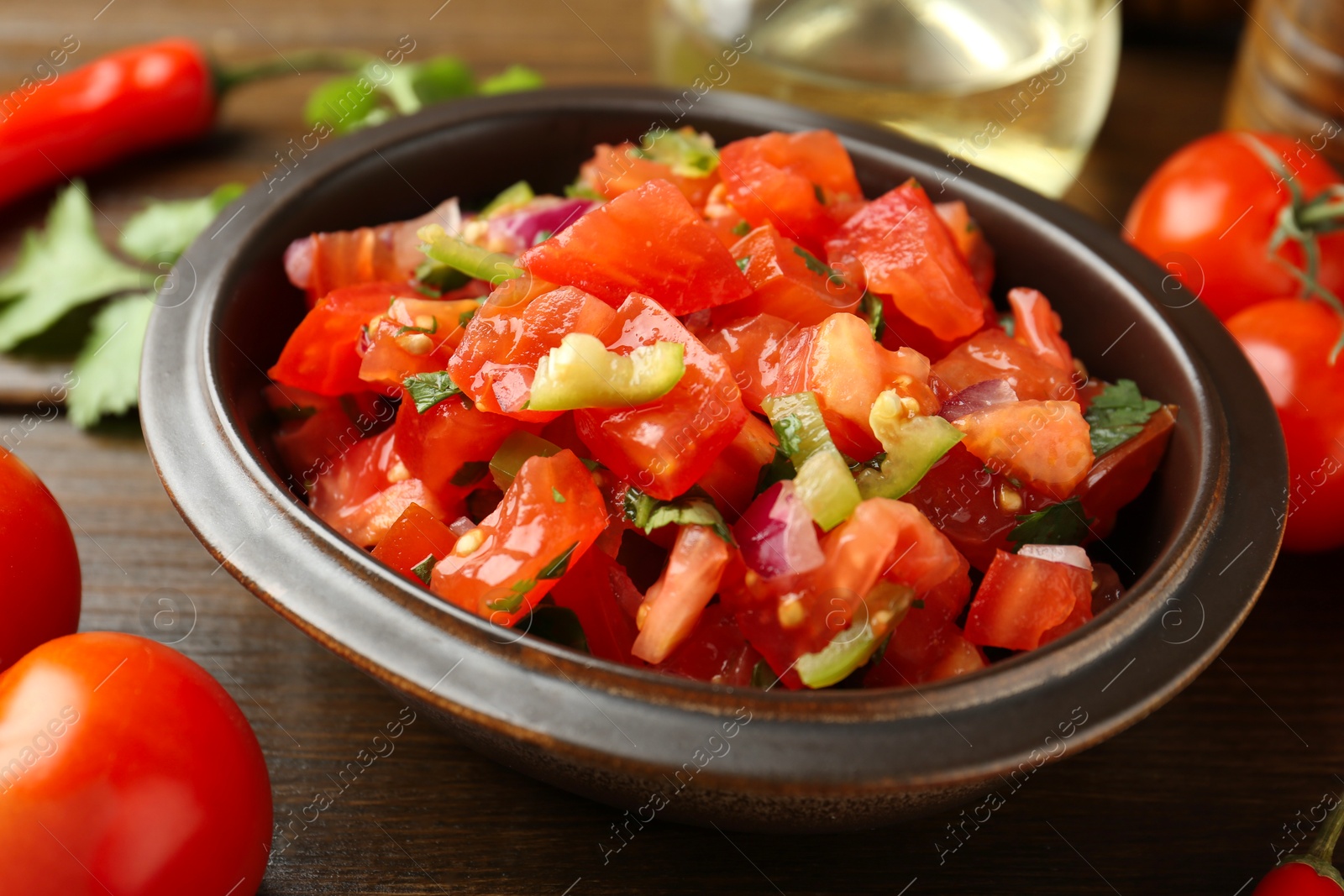 Photo of Delicious spicy salsa with ingredients on wooden table, closeup