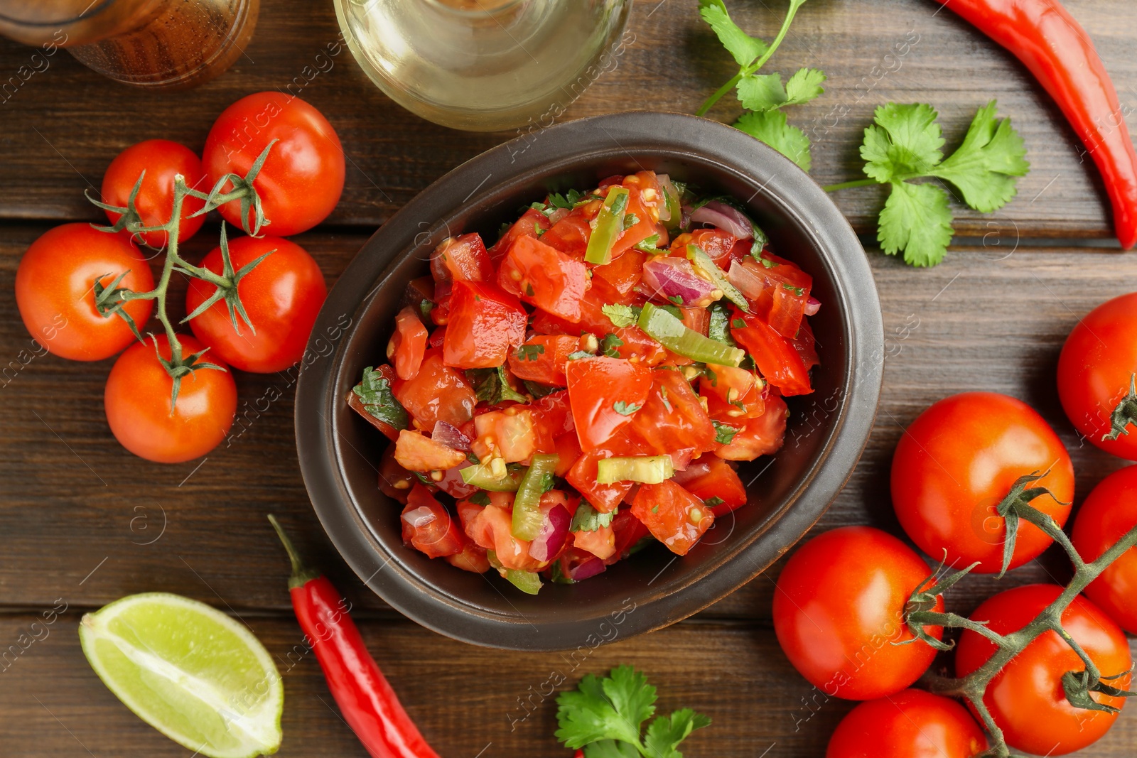 Photo of Delicious spicy salsa with ingredients on wooden table, flat lay