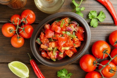 Photo of Delicious spicy salsa with ingredients on wooden table, flat lay