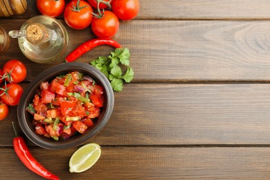 Photo of Delicious spicy salsa with ingredients on wooden table, flat lay. Space for text