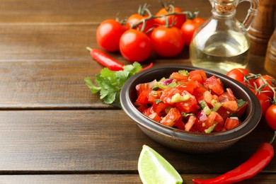 Photo of Delicious spicy salsa with ingredients on wooden table. Space for text