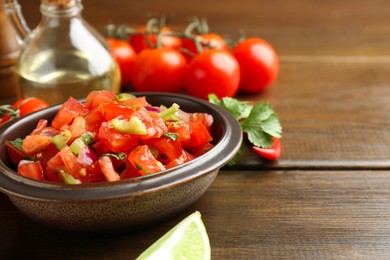 Photo of Delicious spicy salsa with ingredients on wooden table, closeup