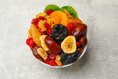 Photo of Mix of different dried fruits in bowl on grey table, top view