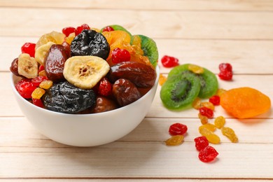 Photo of Mix of different dried fruits in bowl on white wooden table, closeup