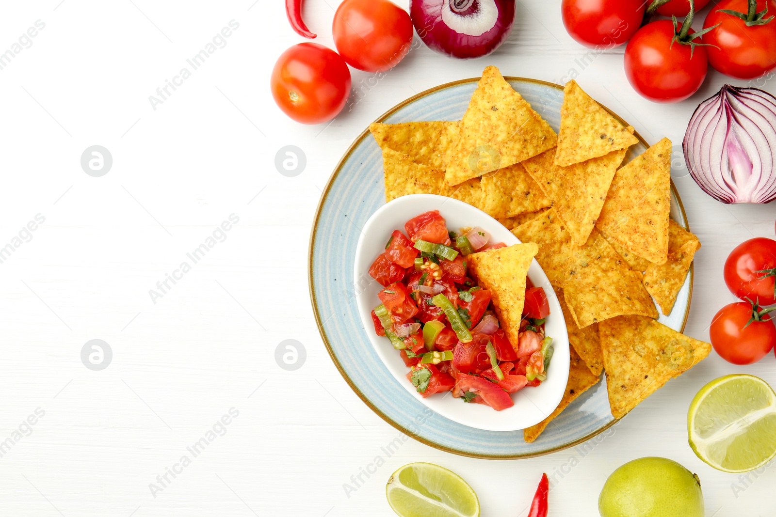 Photo of Delicious salsa (Pico de gallo) served with nachos and products on white wooden table, flat lay. Space for text