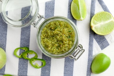 Photo of Delicious salsa sauce in jar and products on white table, flat lay