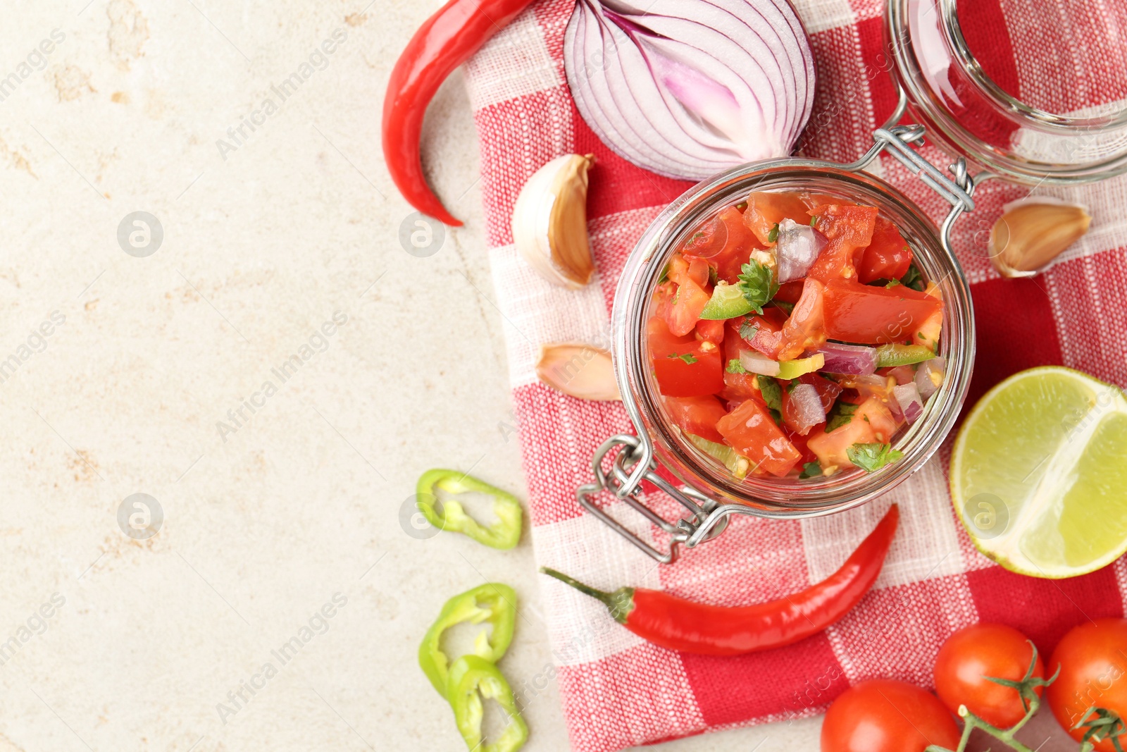 Photo of Delicious salsa (Pico de gallo) in jar and ingredients on light textured table, flat lay. Space for text