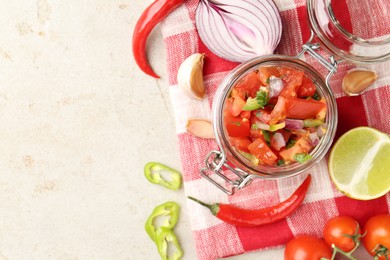 Photo of Delicious salsa (Pico de gallo) in jar and ingredients on light textured table, flat lay. Space for text