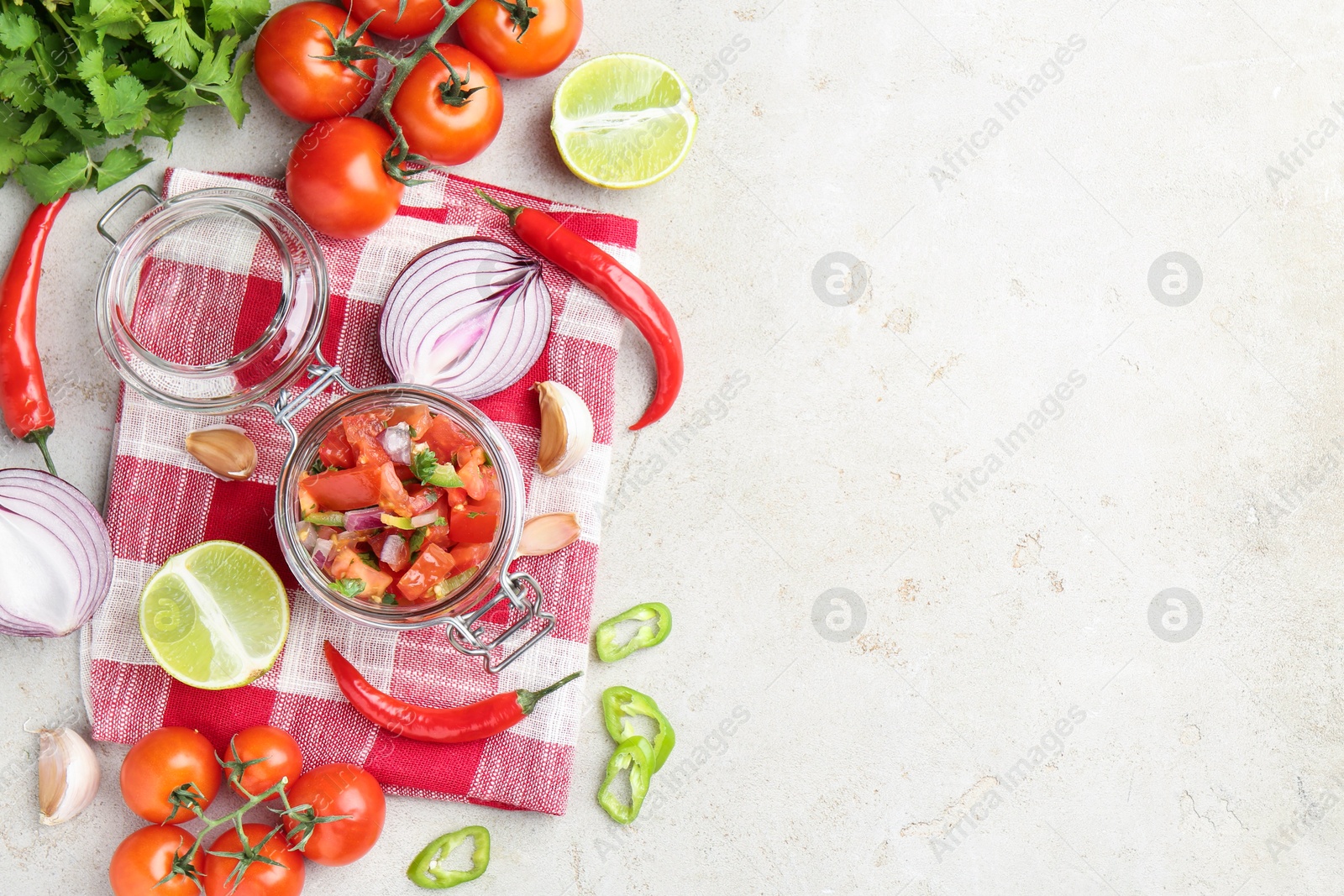 Photo of Delicious salsa (Pico de gallo) in jar and ingredients on light textured table, flat lay. Space for text