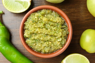 Photo of Delicious salsa sauce in bowl and products on wooden table, flat lay