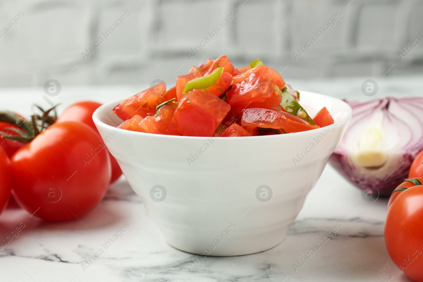 Photo of Delicious salsa, onion and tomatoes on white marble table, closeup