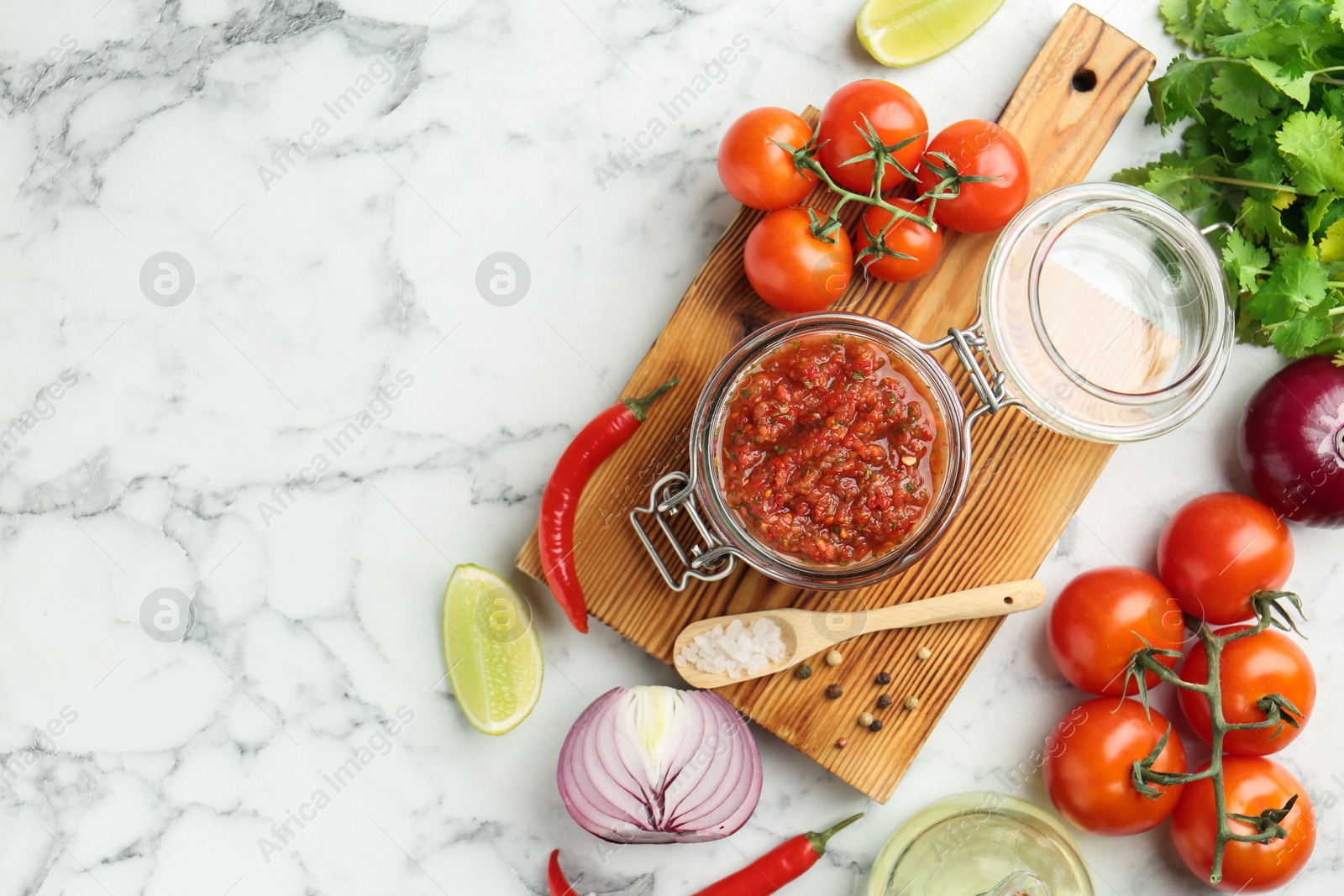 Photo of Spicy salsa and ingredients on white marble table, flat lay. Space for text