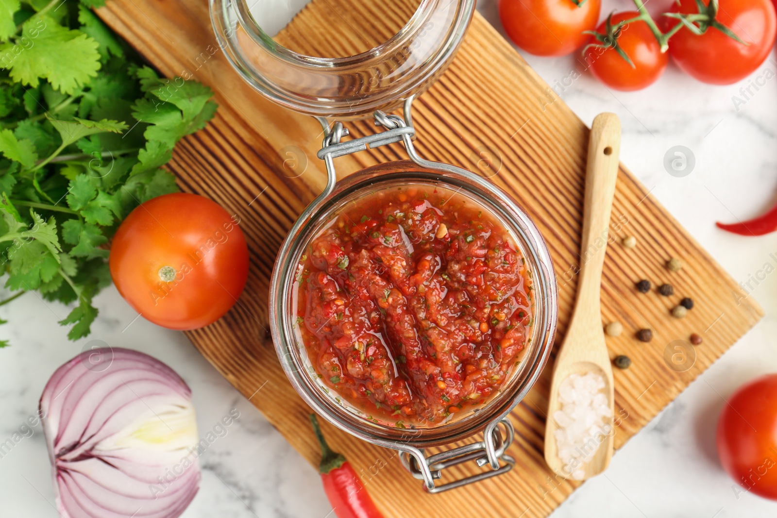 Photo of Spicy salsa and ingredients on white table, top view