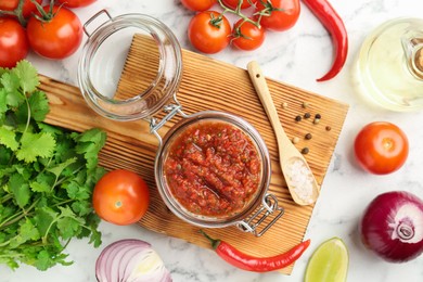 Photo of Spicy salsa and ingredients on white marble table, flat lay