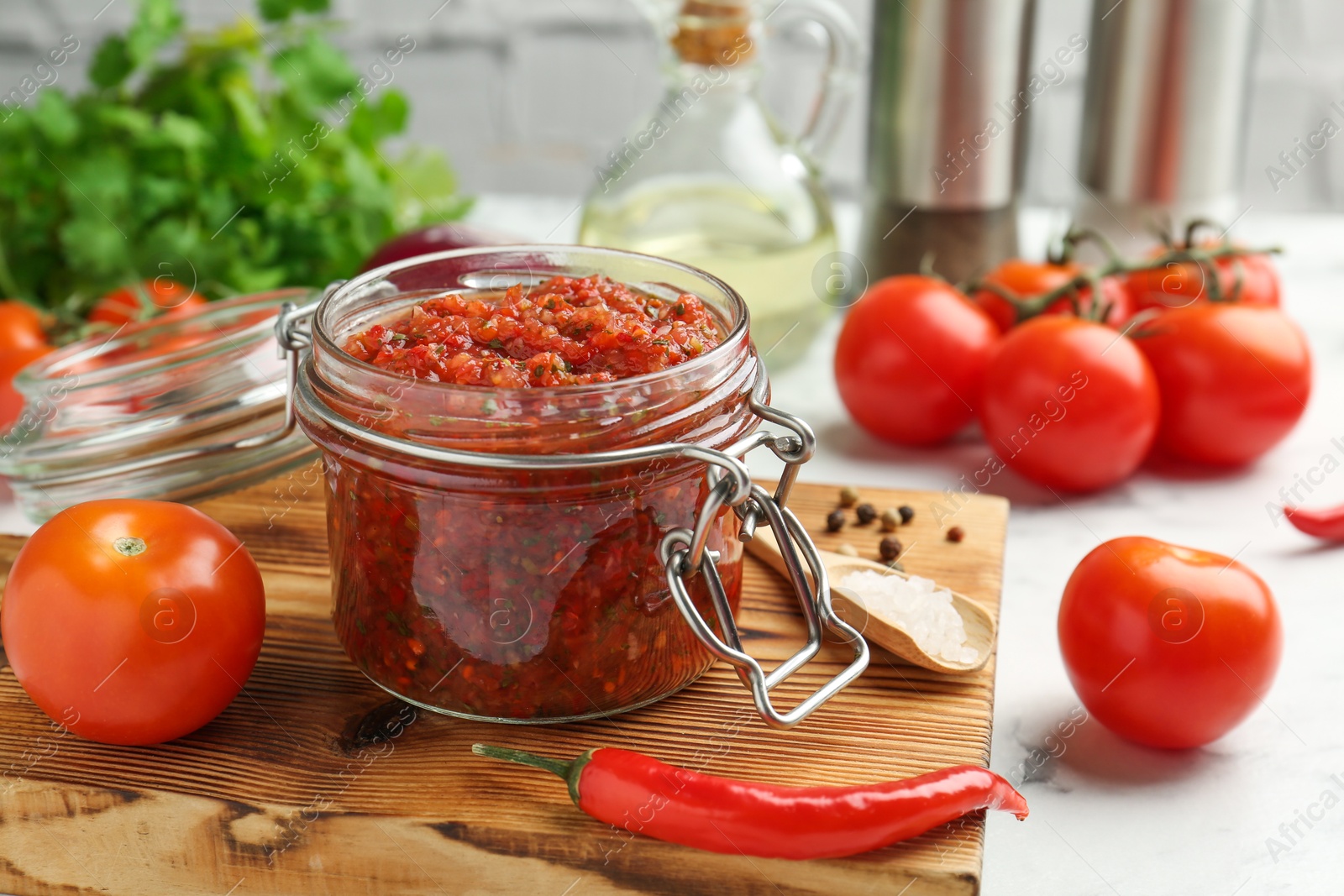 Photo of Spicy salsa and ingredients on white table