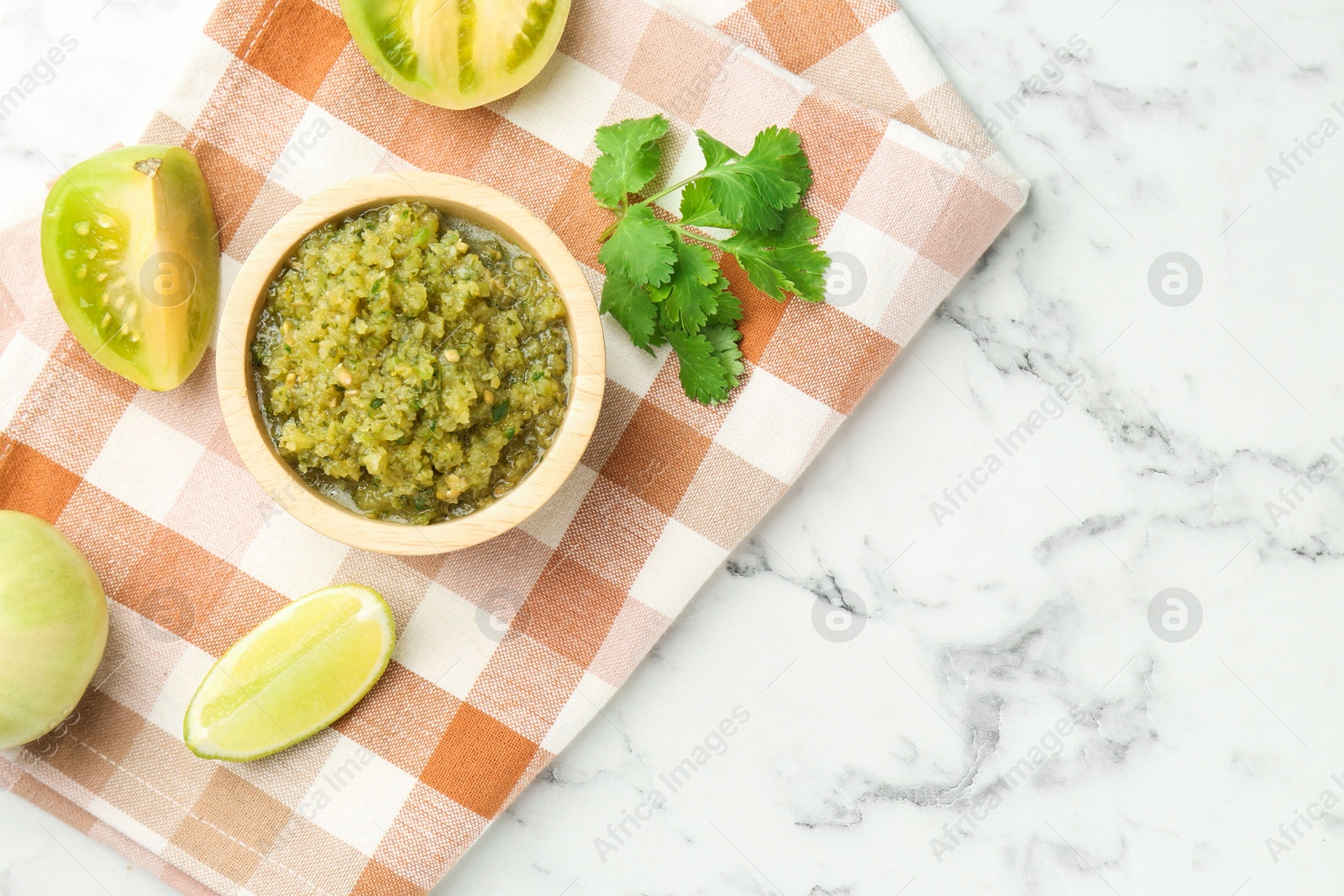 Photo of Spicy salsa and ingredients on white marble table, flat lay. Space for text