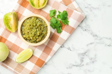 Photo of Spicy salsa and ingredients on white marble table, flat lay. Space for text