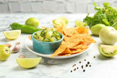 Photo of Delicious salsa with nachos on white marble table