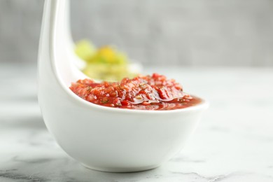 Photo of Sauce boats with salsa on white marble table, selective focus