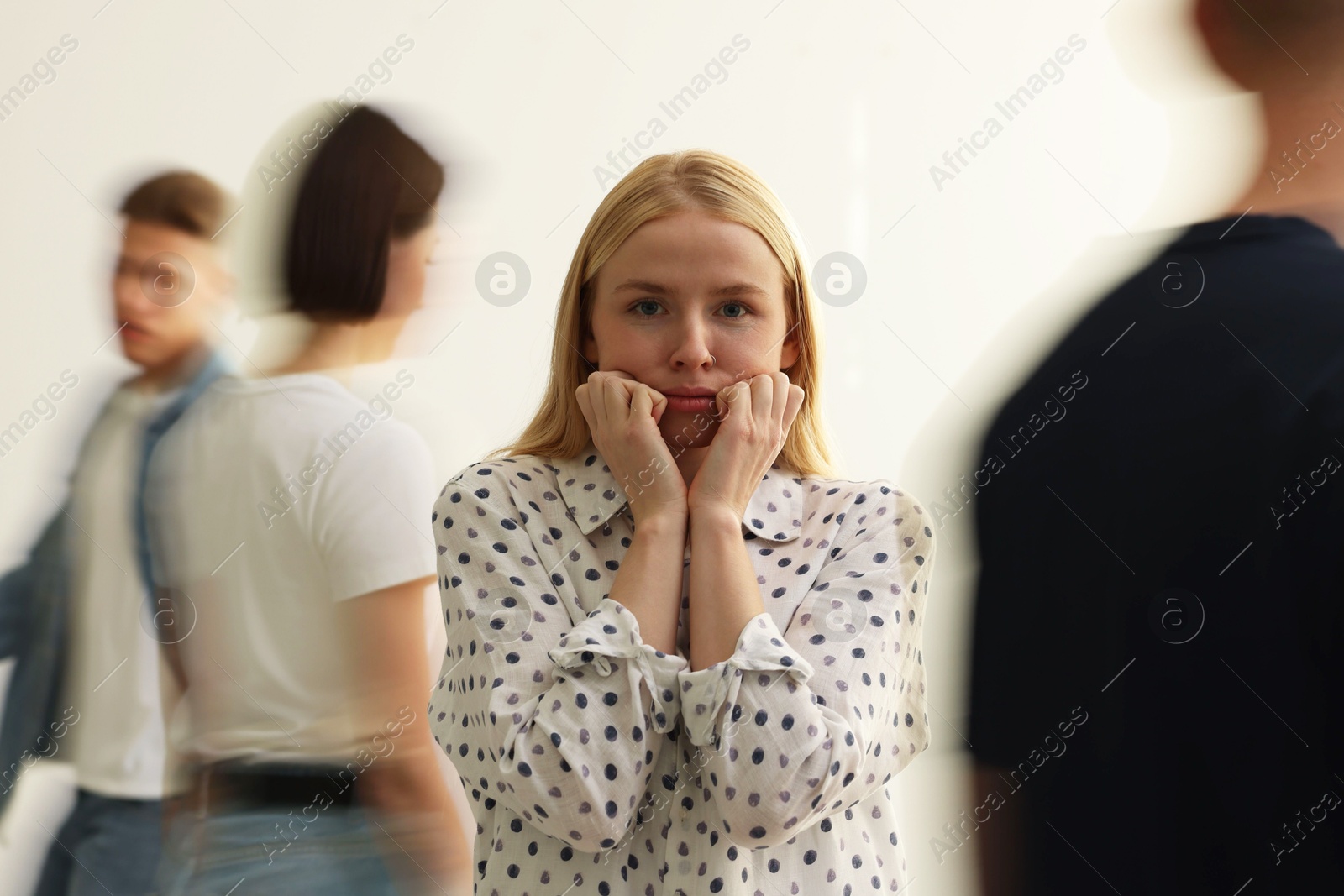 Photo of Young woman feeling uncomfortable among people indoors