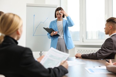 Photo of Glossophobia. Woman with paper tissue and clipboard feeling embarrassed during business meeting in office