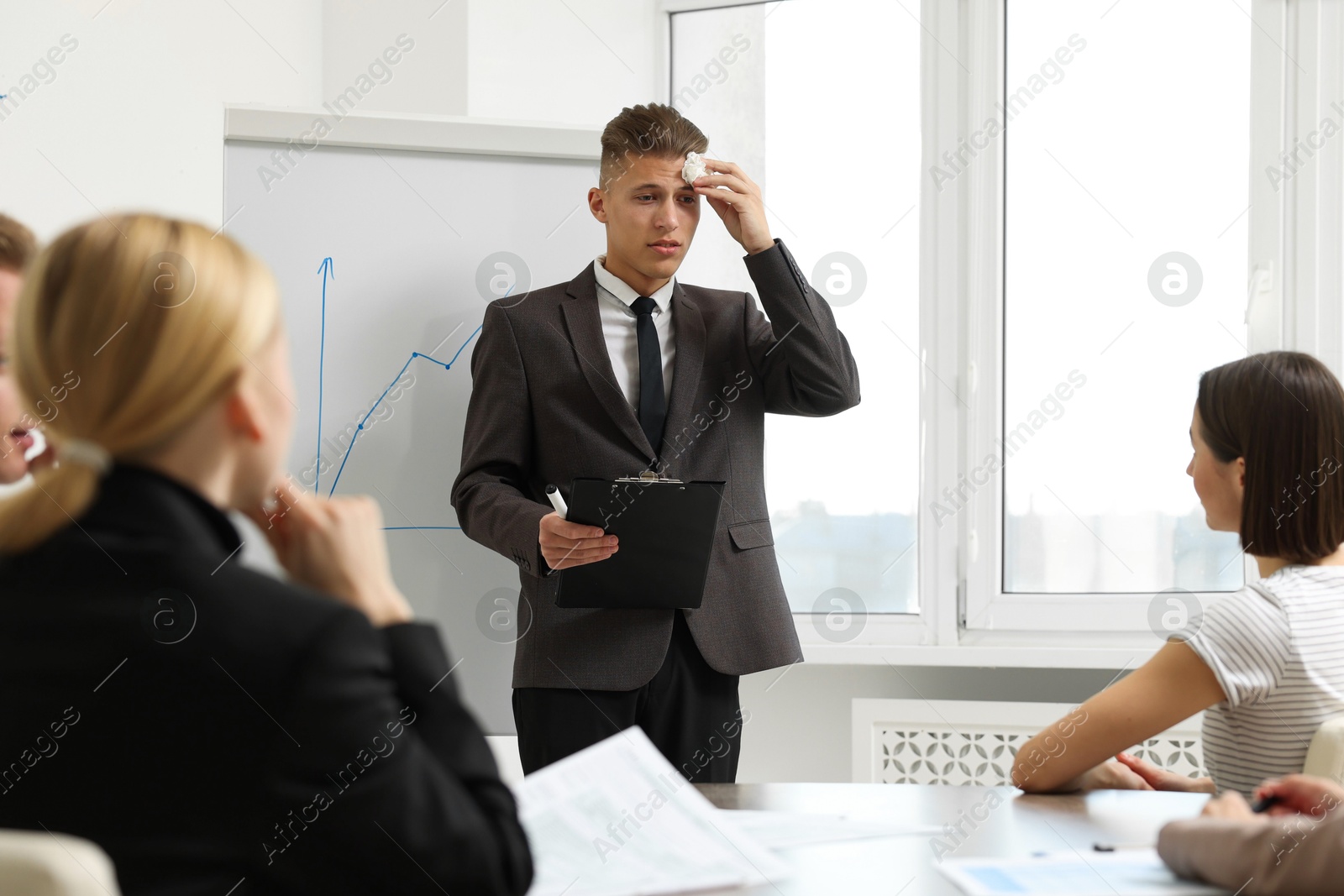 Photo of Glossophobia. Man with paper tissue and clipboard feeling embarrassed during business meeting in office