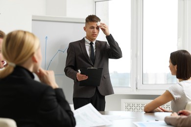 Photo of Glossophobia. Man with paper tissue and clipboard feeling embarrassed during business meeting in office