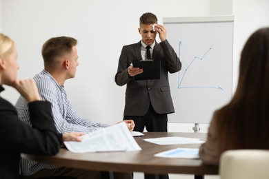 Photo of Glossophobia. Man with paper tissue and clipboard feeling embarrassed during business meeting in office