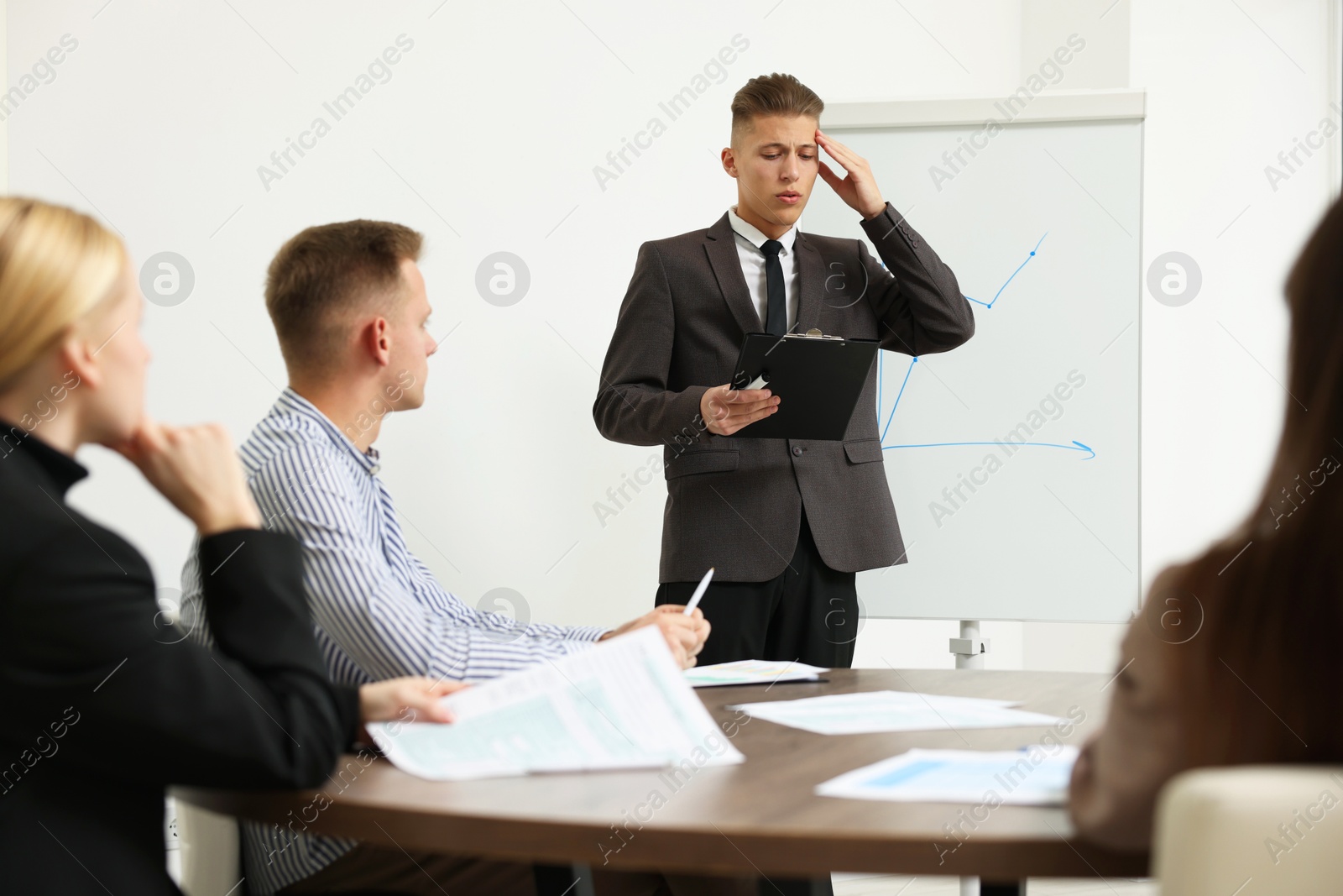 Photo of Glossophobia. Man with clipboard feeling embarrassed during business meeting in office