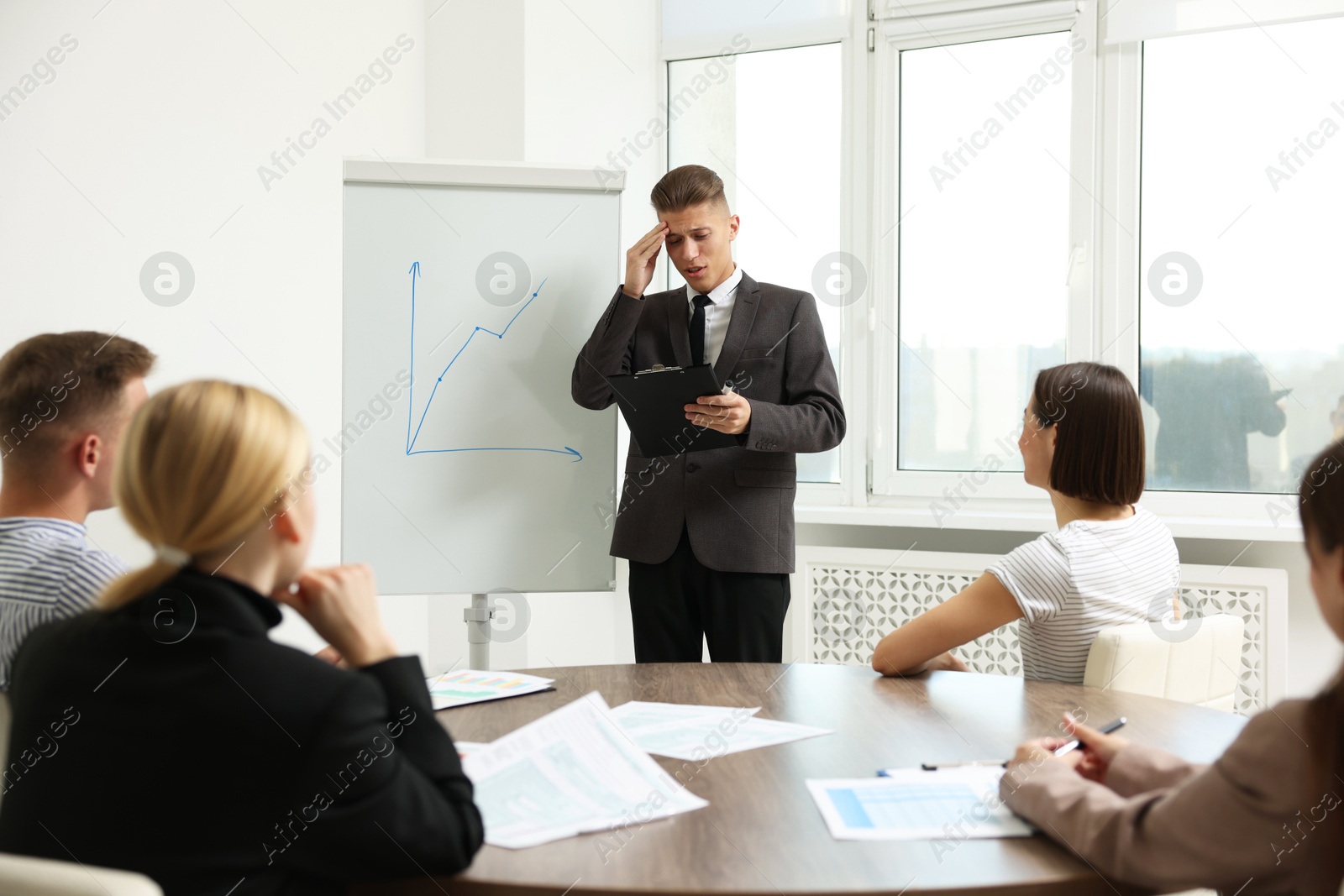 Photo of Glossophobia. Man with clipboard feeling embarrassed during business meeting in office