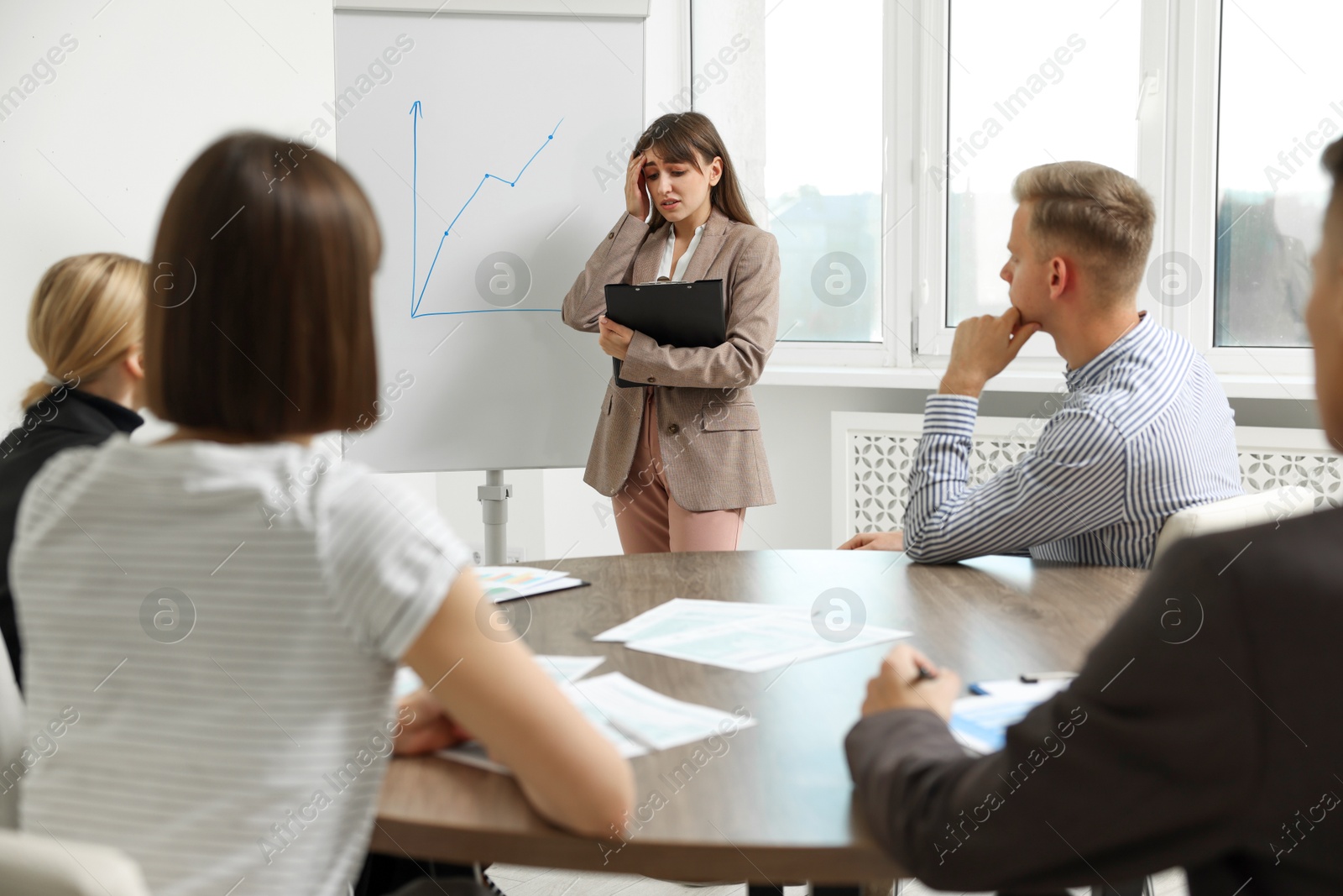 Photo of Glossophobia. Woman with clipboard feeling embarrassed during business meeting in office