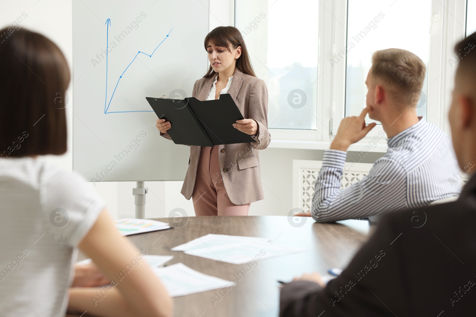 Photo of Glossophobia. Woman with clipboard feeling embarrassed during business meeting in office