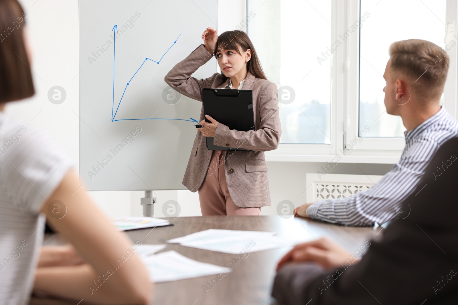 Photo of Glossophobia. Woman with clipboard feeling embarrassed during business meeting in office