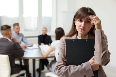 Photo of Glossophobia. Woman with paper tissue and clipboard feeling embarrassed during business meeting in office, selective focus