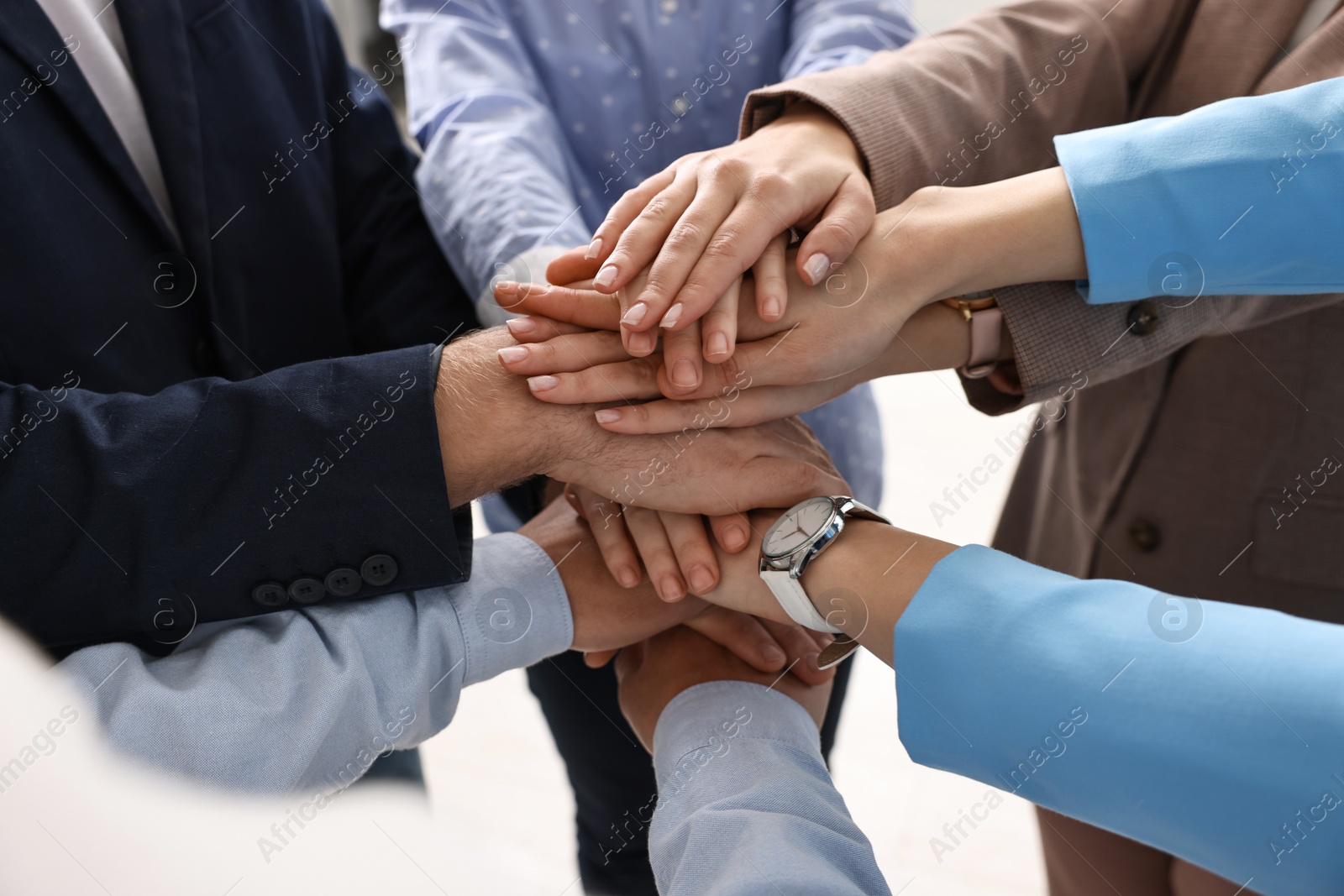 Photo of Teamwork. Group of people joining hands together indoors, closeup