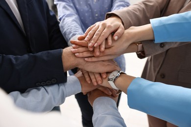 Photo of Teamwork. Group of people joining hands together indoors, closeup