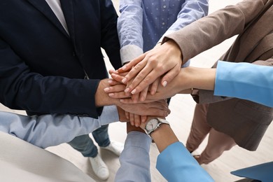 Photo of Teamwork. Group of people joining hands together indoors, above view