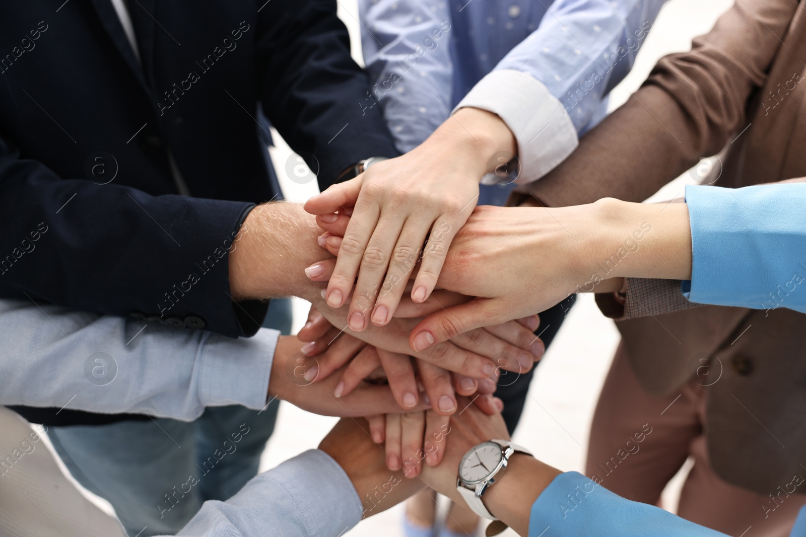 Photo of Teamwork. Group of people joining hands together indoors, closeup