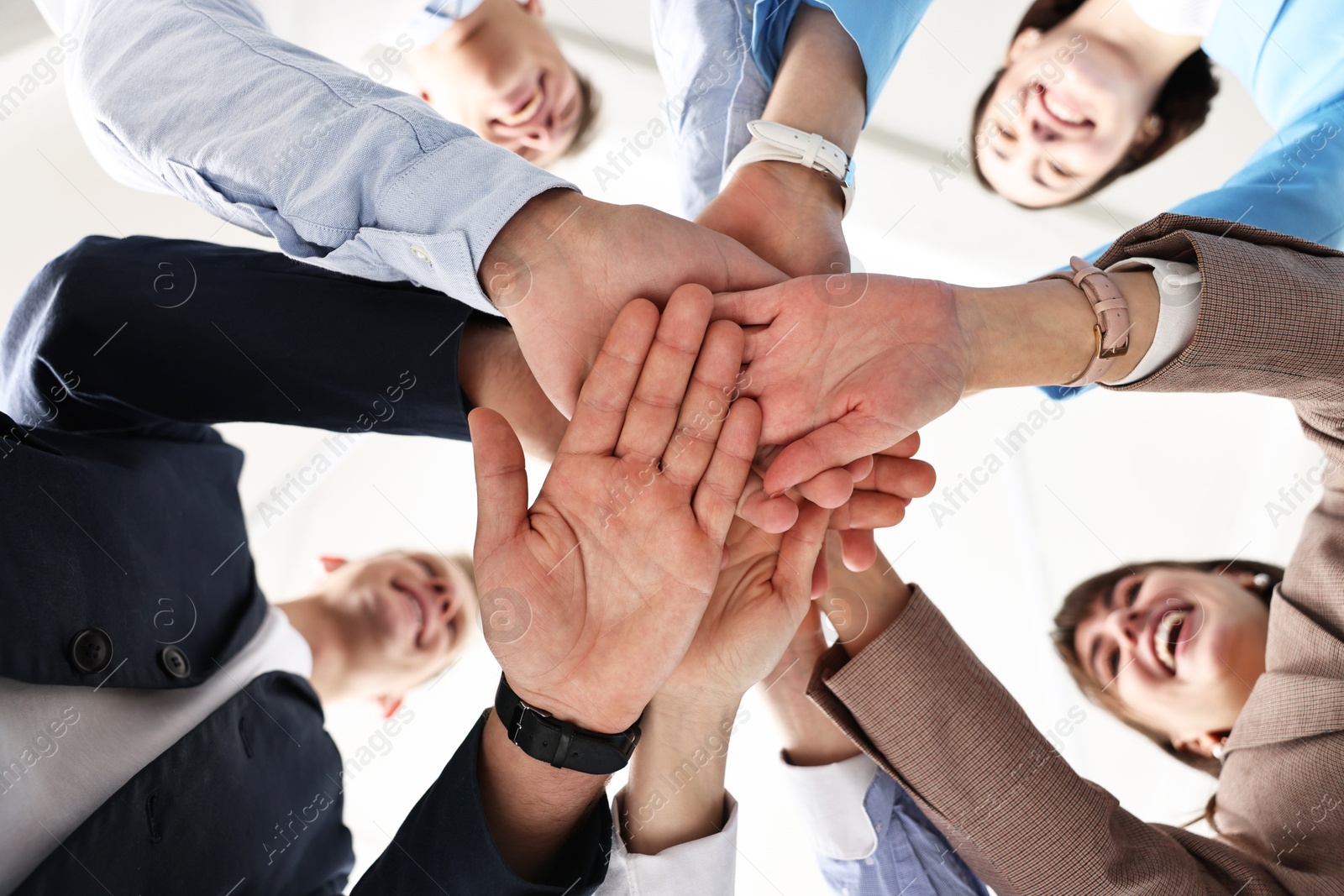 Photo of Teamwork. Group of people joining hands together indoors, bottom view